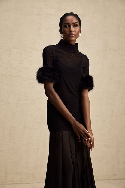 Woman wearing black sleeveless top with faux fur trim and sheer tulle overlay