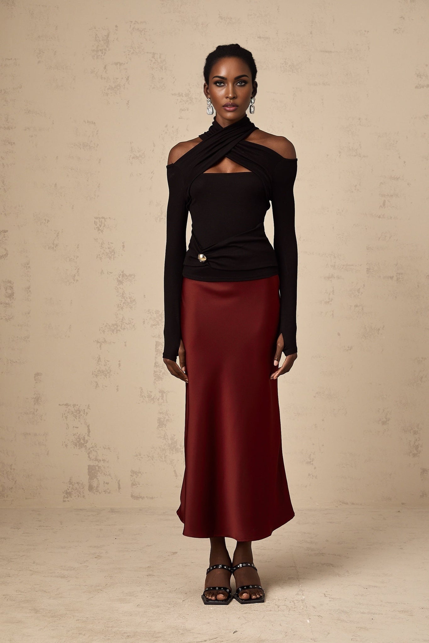 Woman wearing a black formfitting top with ruched details and long sleeves made from stretchy jersey fabric