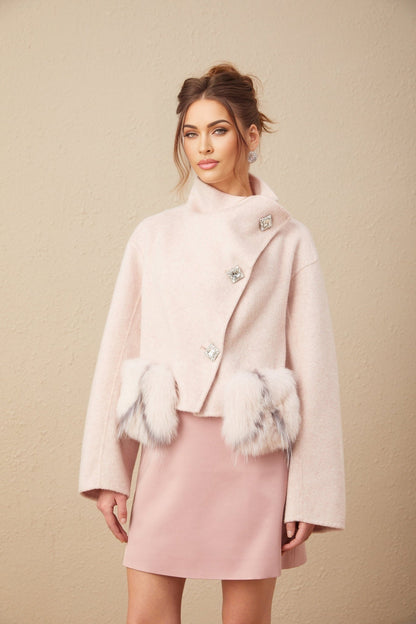 Woman wearing a short pink coat with diagonal button placket standing against a plain background