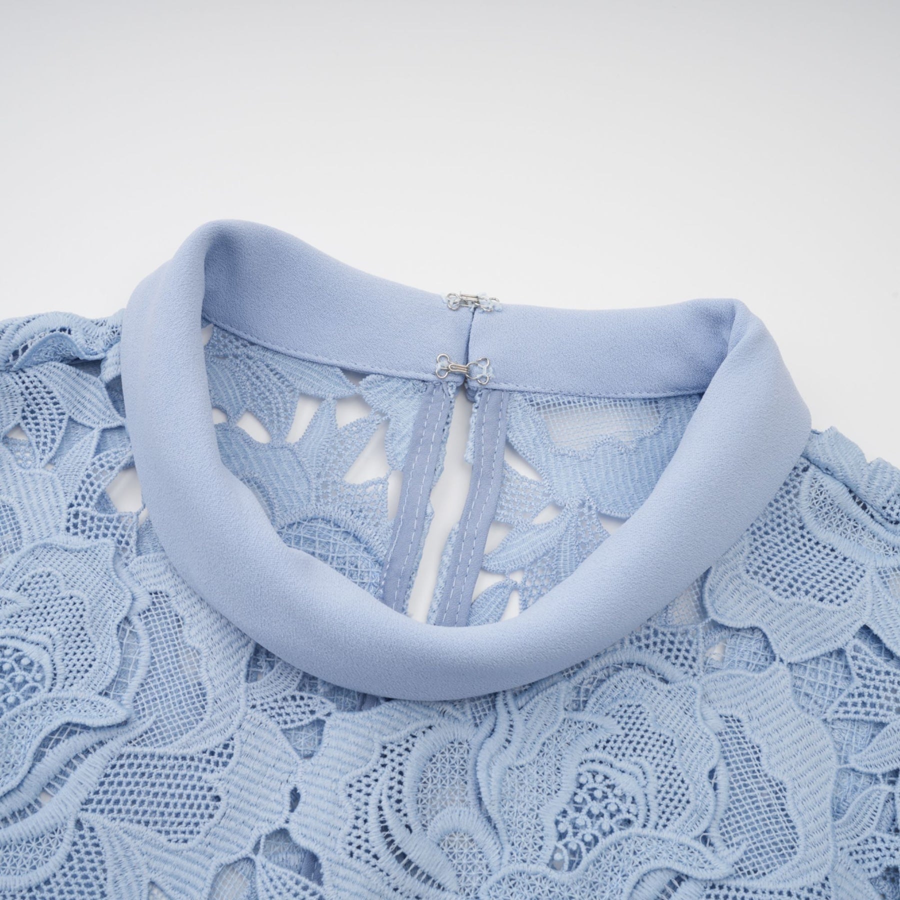 A blue midi dress with floral lace appliqués and a delicate floral pattern throughout the fabric