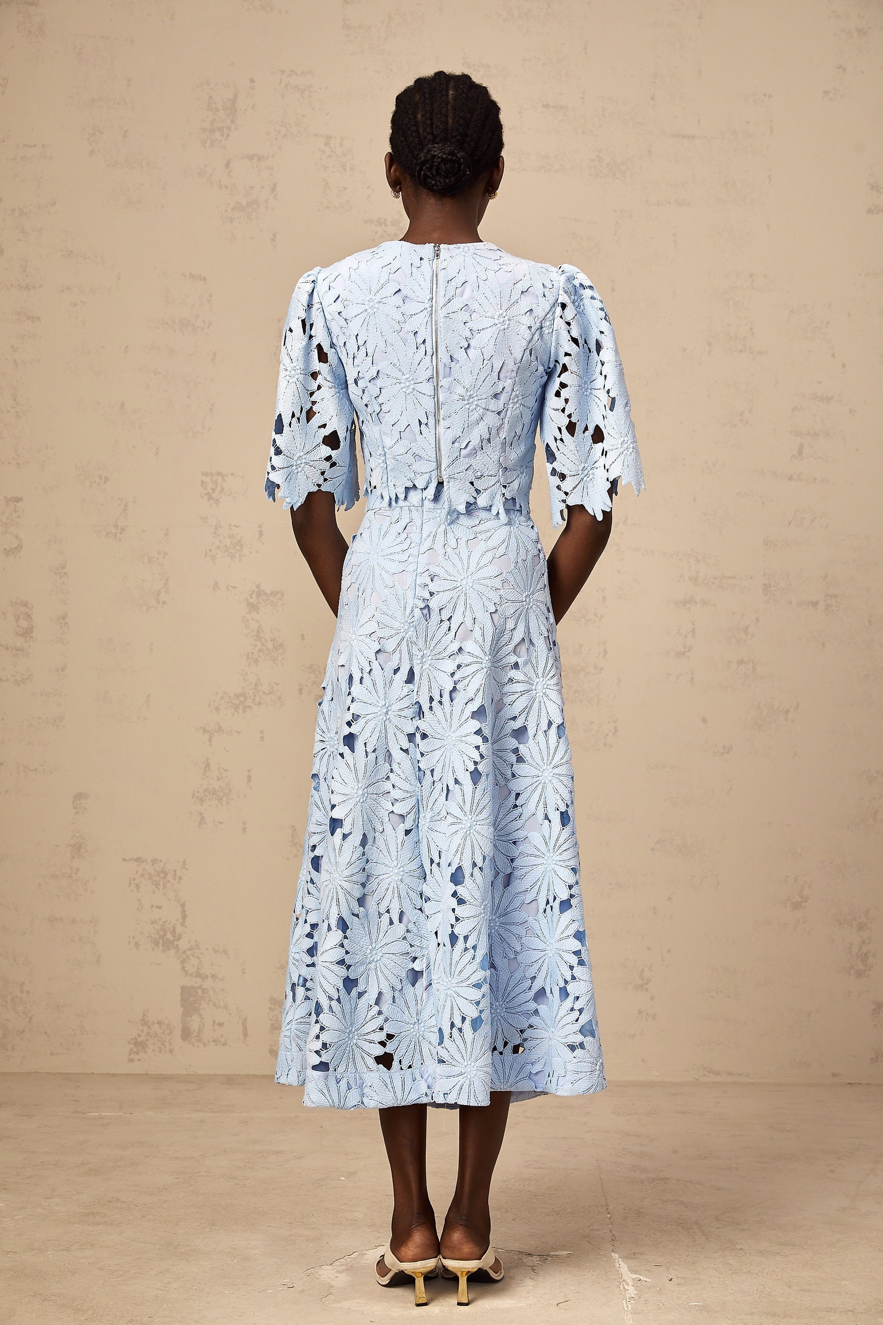 Woman wearing a blue lace top and matching skirt set in Audrey style with guipure lace detailing