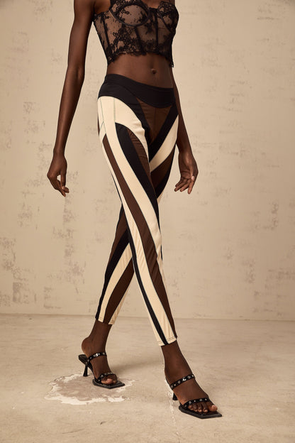Woman wearing spiral color block panelled leggings in vibrant colors with a swirling pattern on the legs