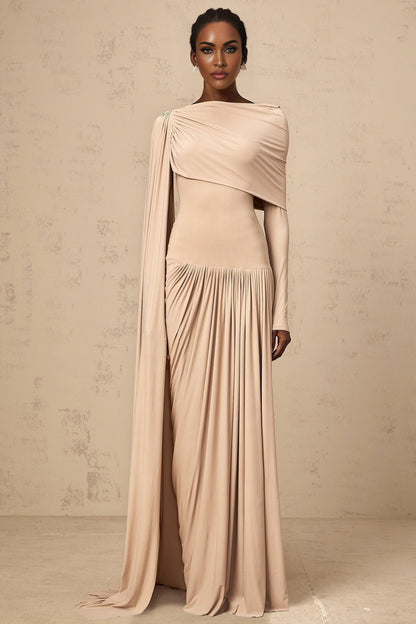 Woman wearing long flowing neutral colored maxi dress with ribbon design details and draped silhouette