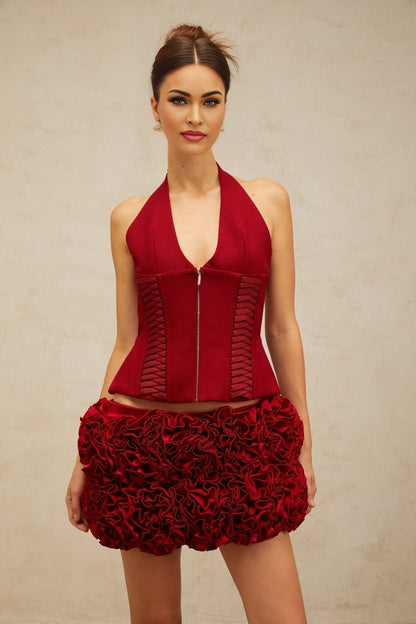 Woman wearing a red halterneck top with lace up detail