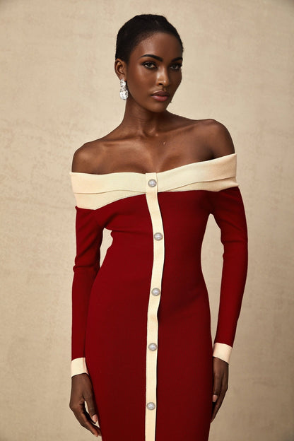 Woman wearing blue offshoulder knit midi dress with fitted silhouette standing against plain background