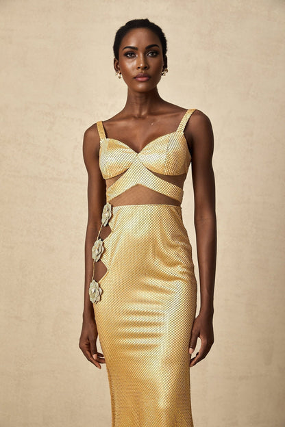 A long gold maxi dress with floral cutout details and a flowing silhouette