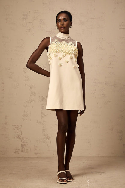 A sleeveless mini dress with floral pattern featuring faux flowers on a light background