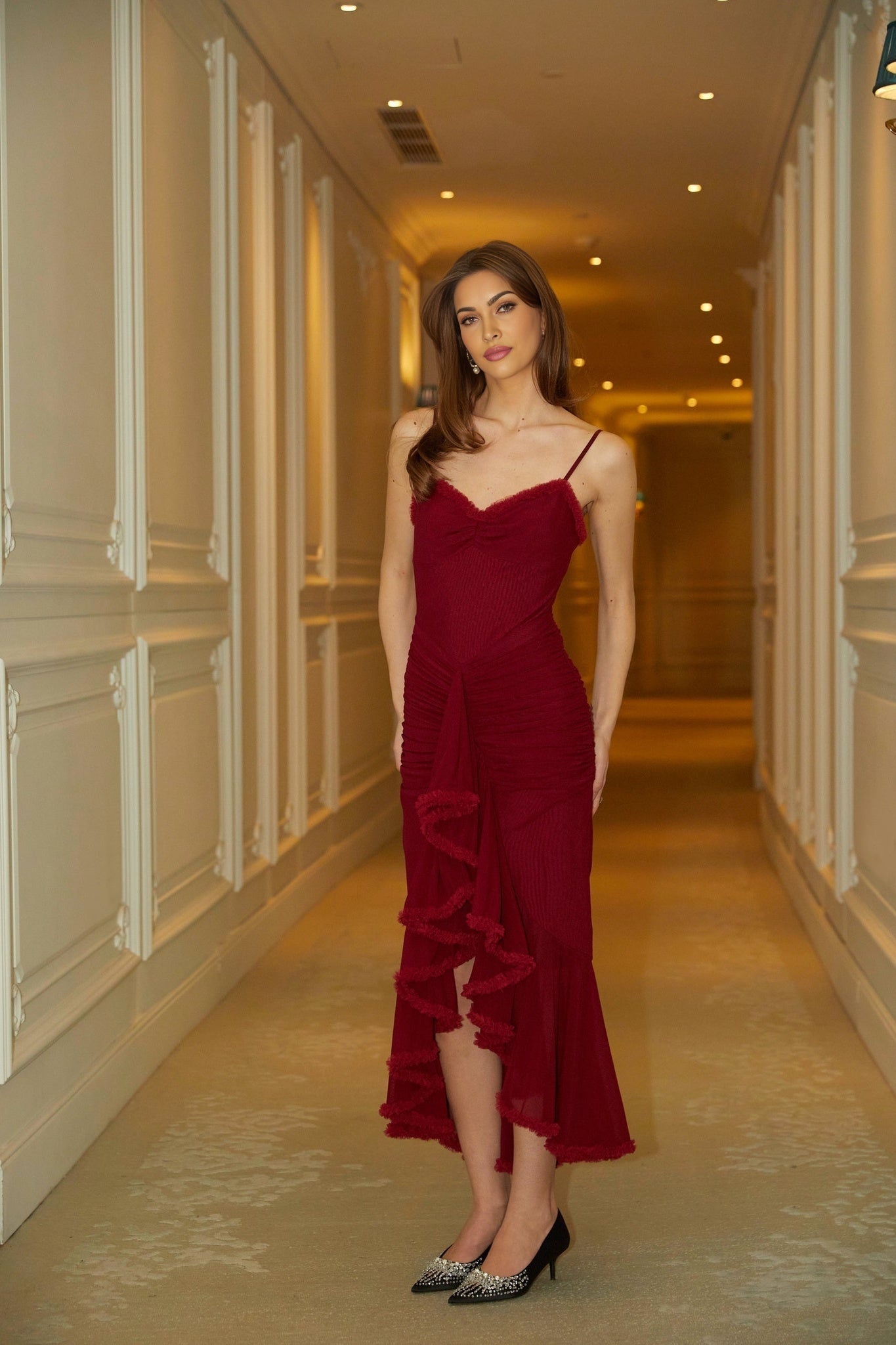 A red maxi dress with ruffle details and draped fabric featuring a long flowing silhouette