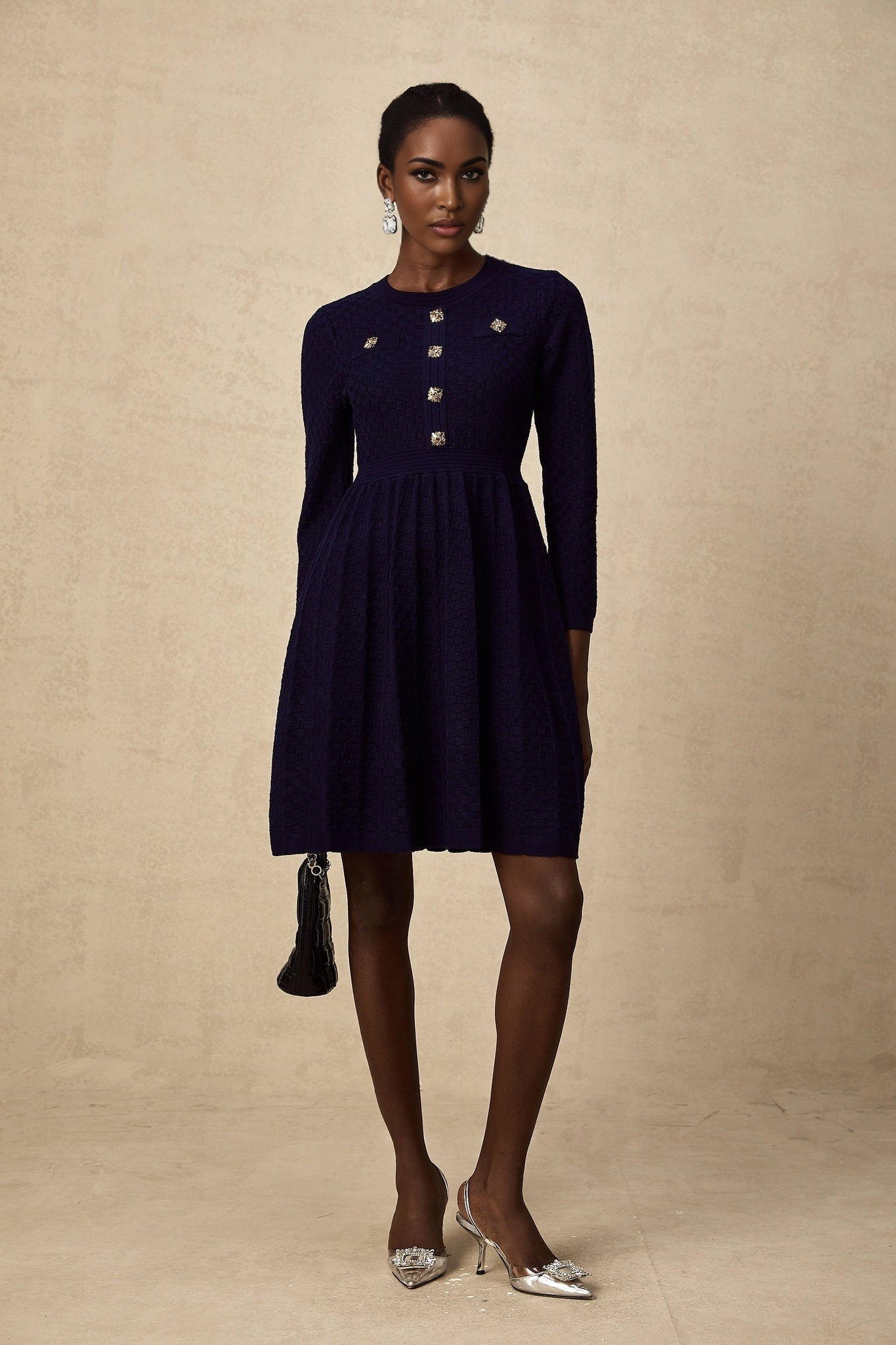 A navy blue mini dress with a basketweave texture worn by a female model standing against a plain background