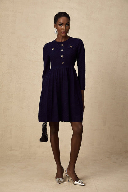 A navy blue mini dress with a basketweave texture worn by a female model standing against a plain background