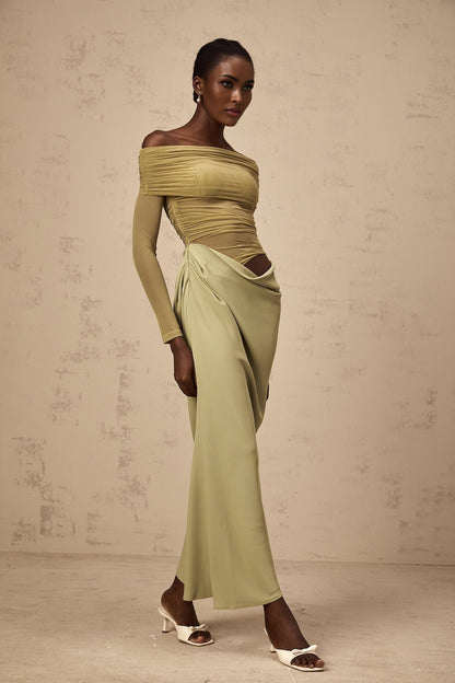 Woman wearing green off shoulder midi dress with sheer elements standing in relaxed pose