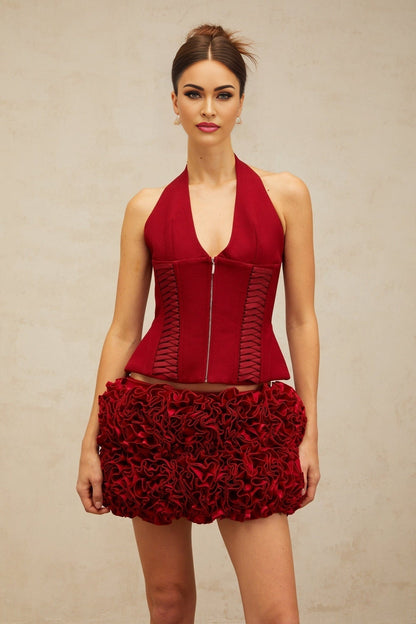 Woman wearing bright red halterneck top with laceup detail at front