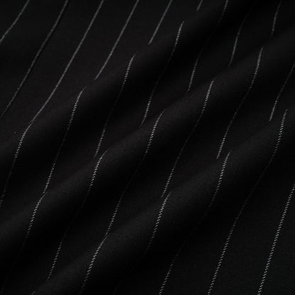 Woman wearing a black blazer with white stripes and an open back design