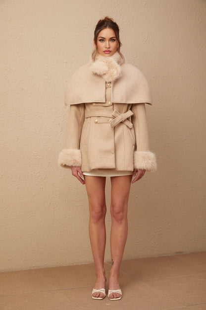 Woman wearing long white faux fur coat with detachable cape collar