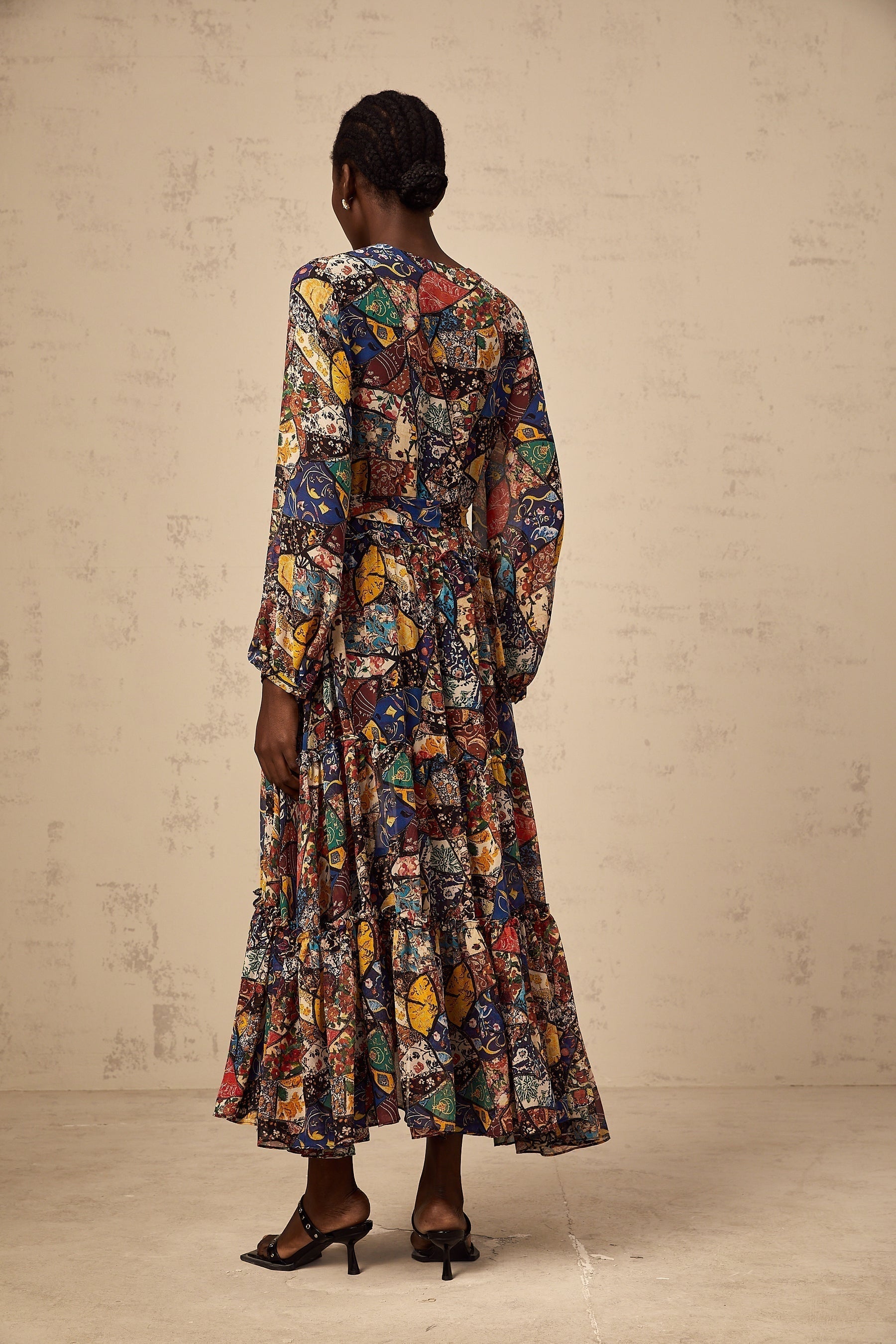 Woman wearing a brown bohemian style midi dress with shirring details and flowy sleeves in an outdoor setting