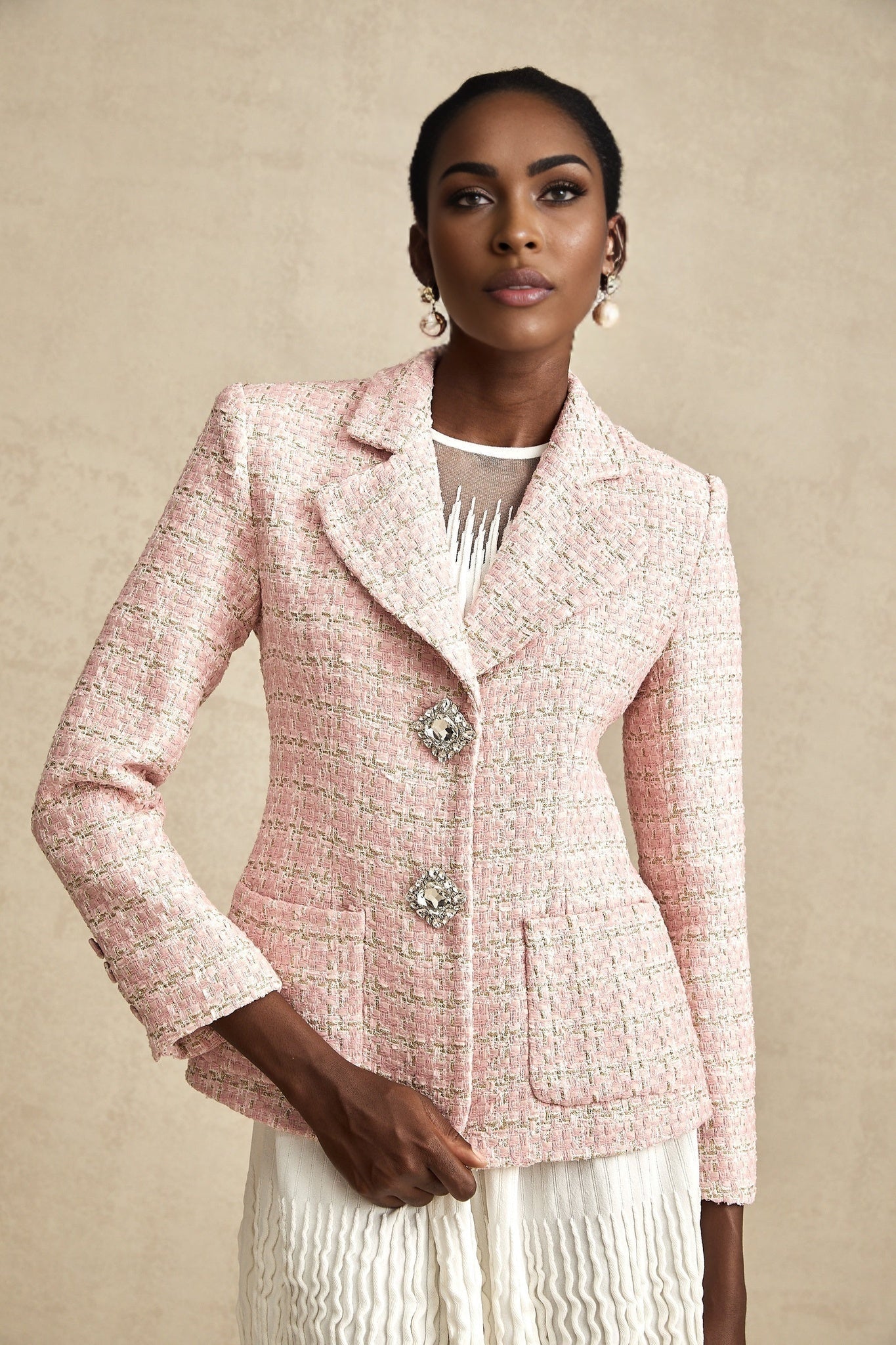 Woman wearing a pink tweed blazer with crystal embellishments and a checked pattern