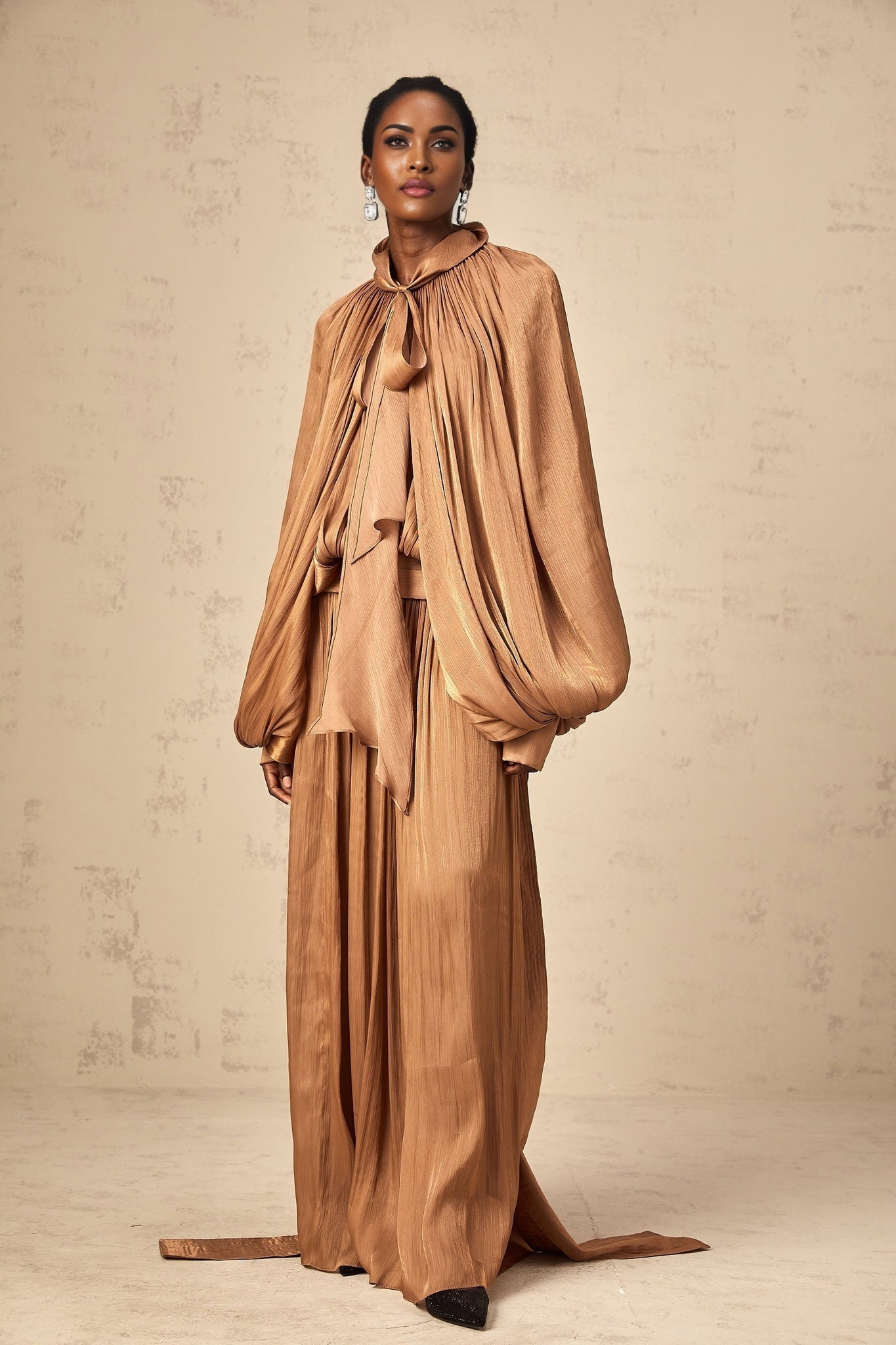 Long brown satin maxi dress with pleated details and a flowing skirt