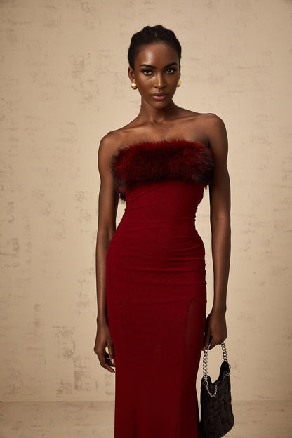 A woman wearing a red offshoulder midi dress with faux fur trim and mesh detailing
