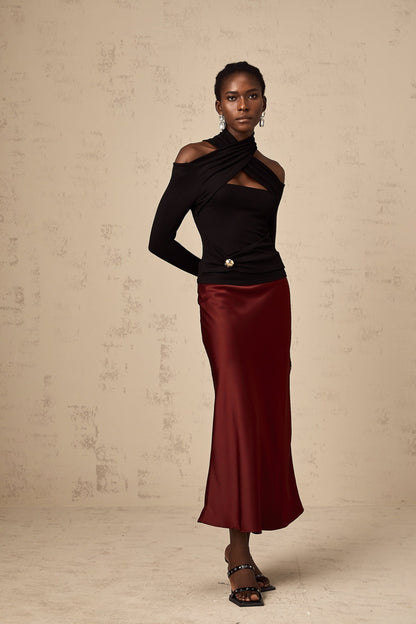 A red satin skirt with a flared silhouette hanging on a plain background