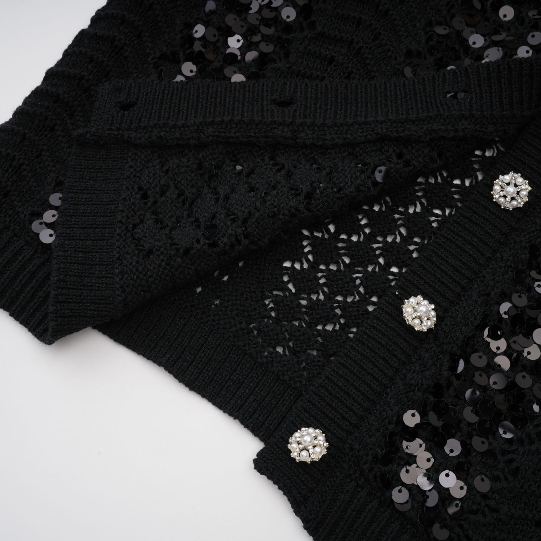 Woman wearing a black sequined matching set with crochet knit cardigan and skirt