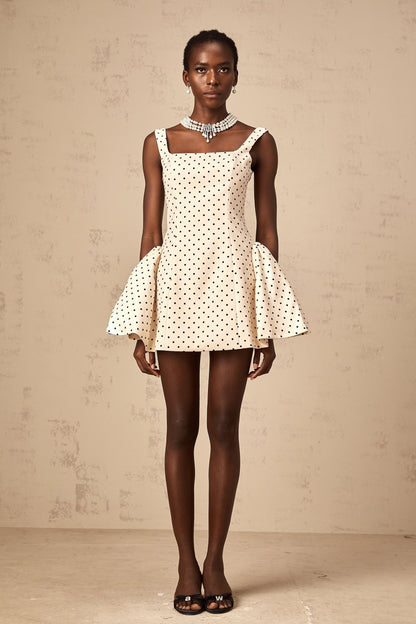Woman wearing neutral colored mini dress with polka dot pattern and puff sleeves