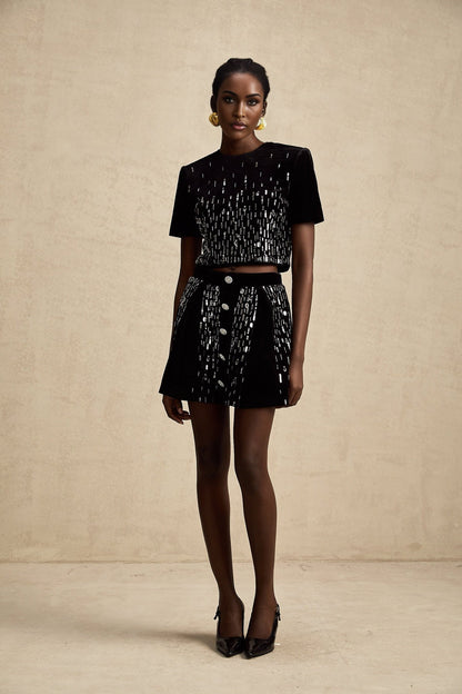 Woman wearing black velvet matching set consisting of embellished top and skirt called Isabeau