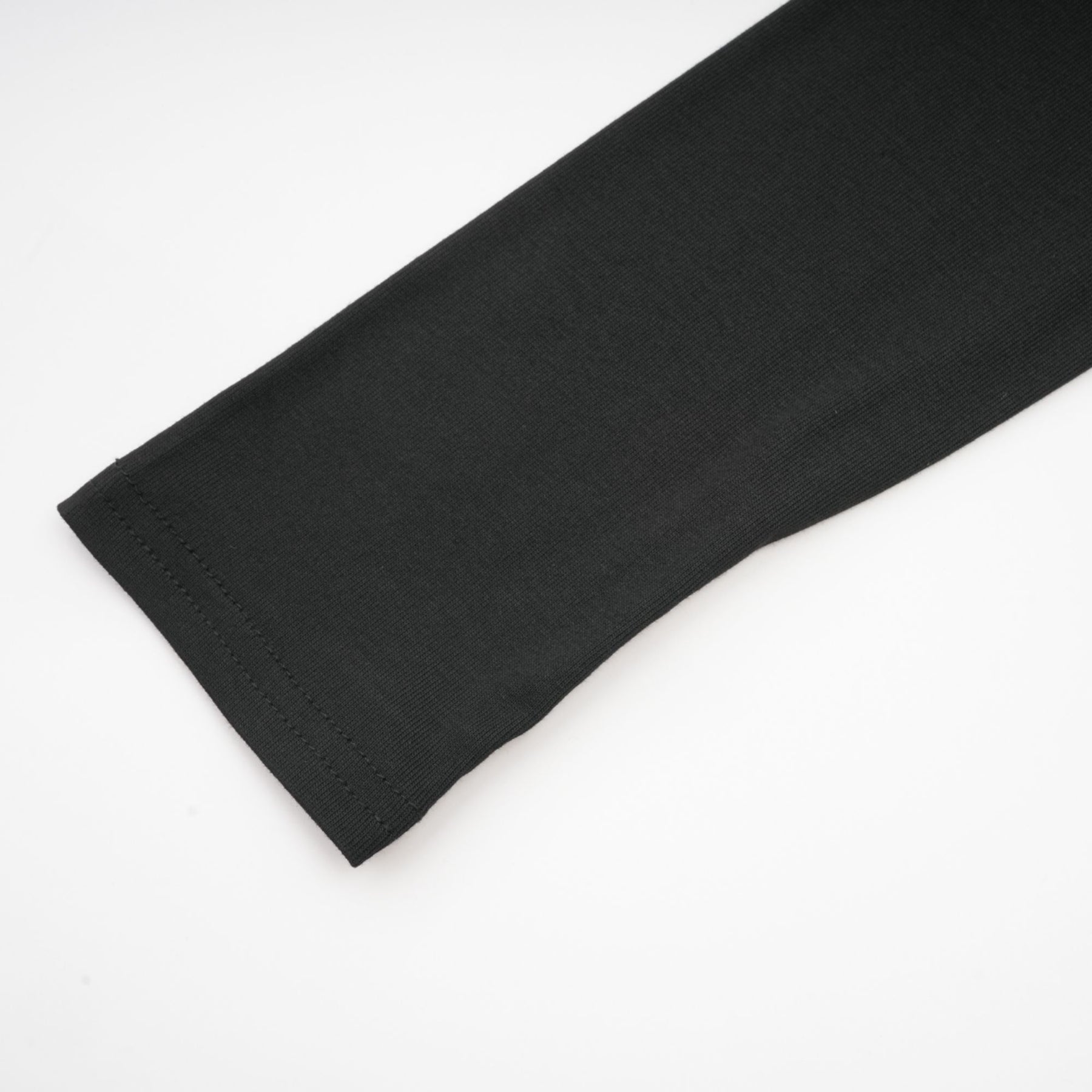 A black ruched top with long sleeves made of stretchy jersey fabric named Odette