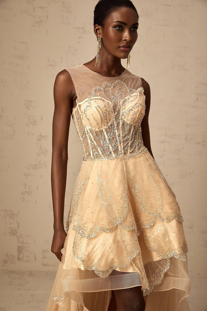 Woman wearing champagne colored sleeveless gown with embellished bodice and high low skirt with floral daisy pattern