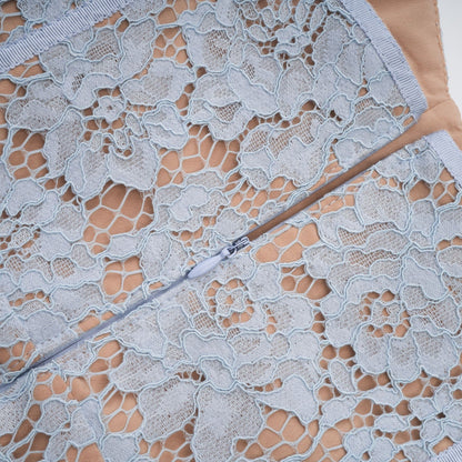 A woman wearing a blue midi dress with floral lace pattern and boned bodice