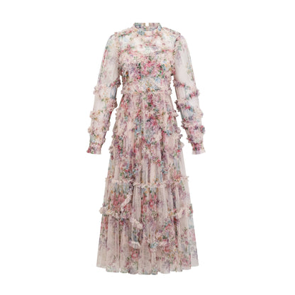 Young woman wearing a floral patterned midi dress with ruffled tulle details and a fitted bodice standing in a garden setting