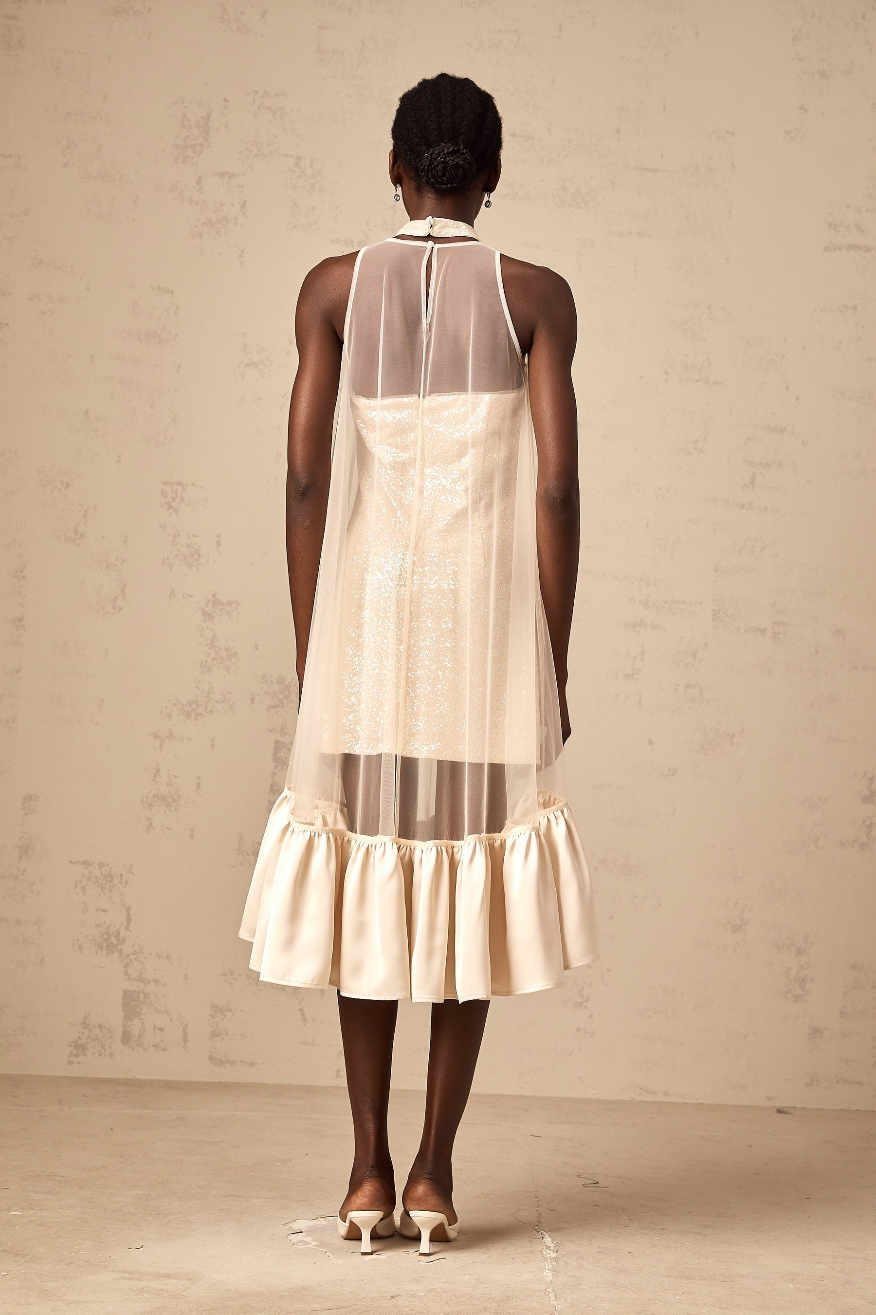 A glamorous midi dress with a layered skirt featuring sequin embellishments and sheer tulle panels adding elegance and texture to the design