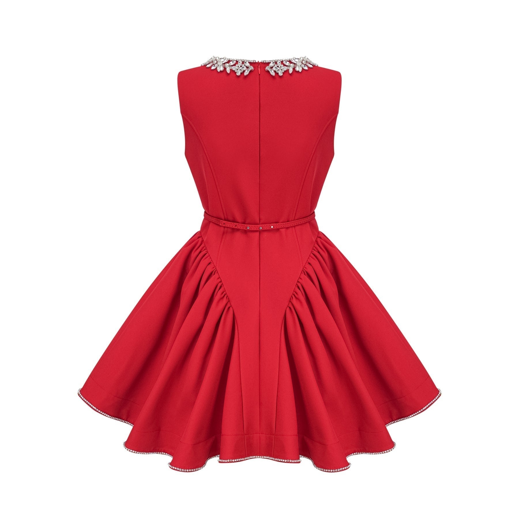 Young woman wearing a red pleated mini dress with embellishments standing in front of a plain background