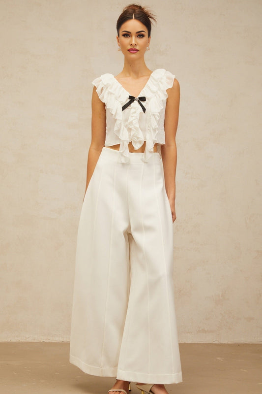 Young woman wearing white chiffon cropped top with bow detail and ruffle accents