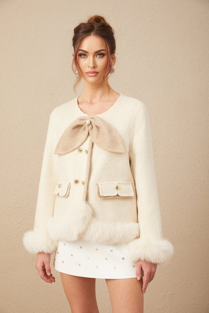 Woman wearing a short coat with contrasting colors and a large bow detail at the front