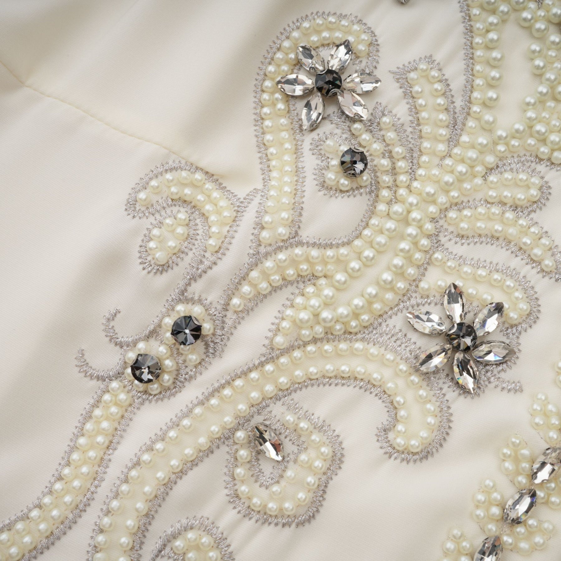Woman wearing white jacket and dress set with pleated details and embellishments