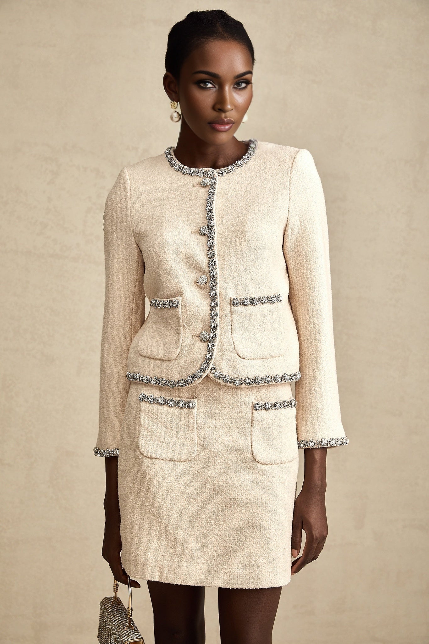 Woman wearing beige tweed cardigan and matching skirt set with crystal embellishments Elisabeth style outfit against plain background