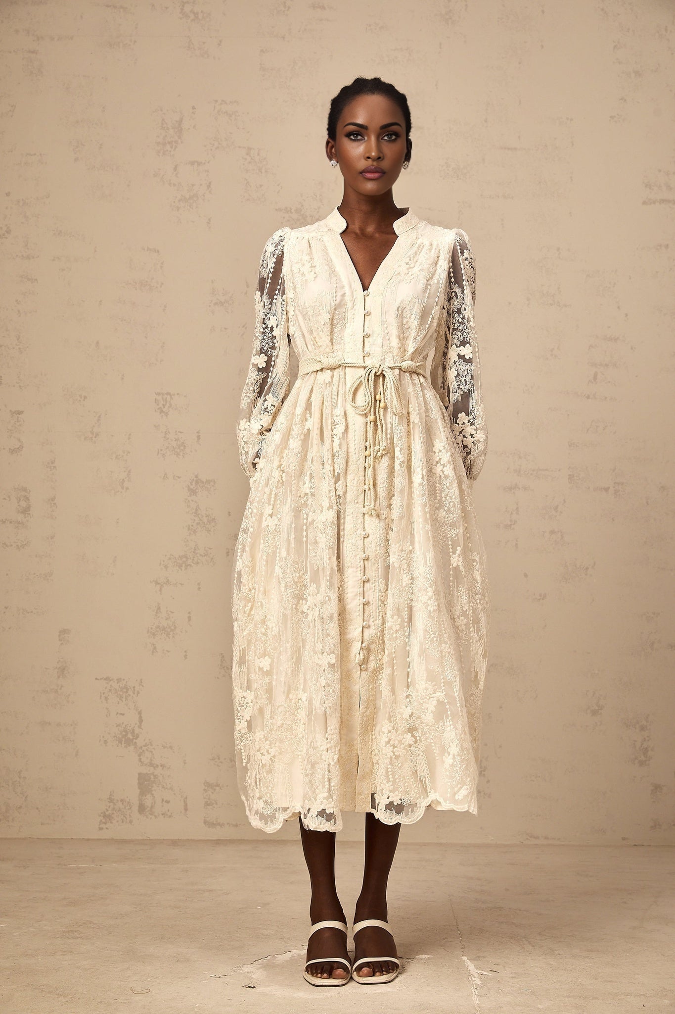 Woman wearing a beige midi dress with lace embroidery details and a fitted silhouette