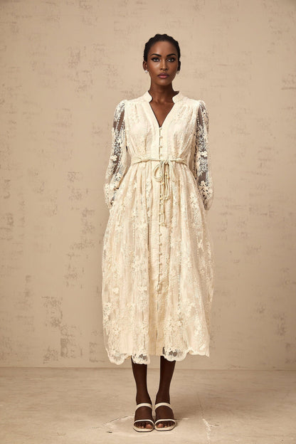 Woman wearing a beige midi dress with lace embroidery details and a fitted silhouette
