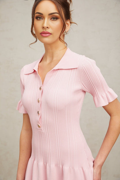 Young woman wearing a pink mini dress with flared short sleeves and skirt made of fine knit fabric