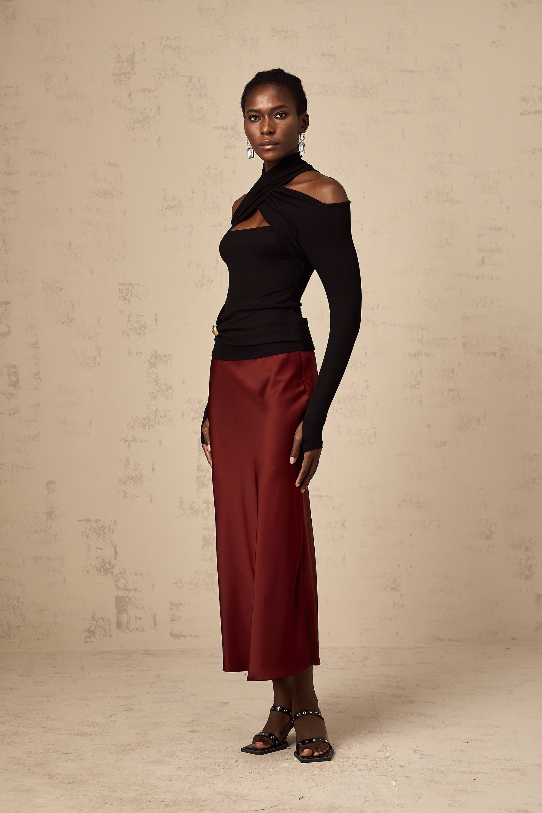 Young woman wearing a vibrant red satin skirt with a flared silhouette standing against a plain background