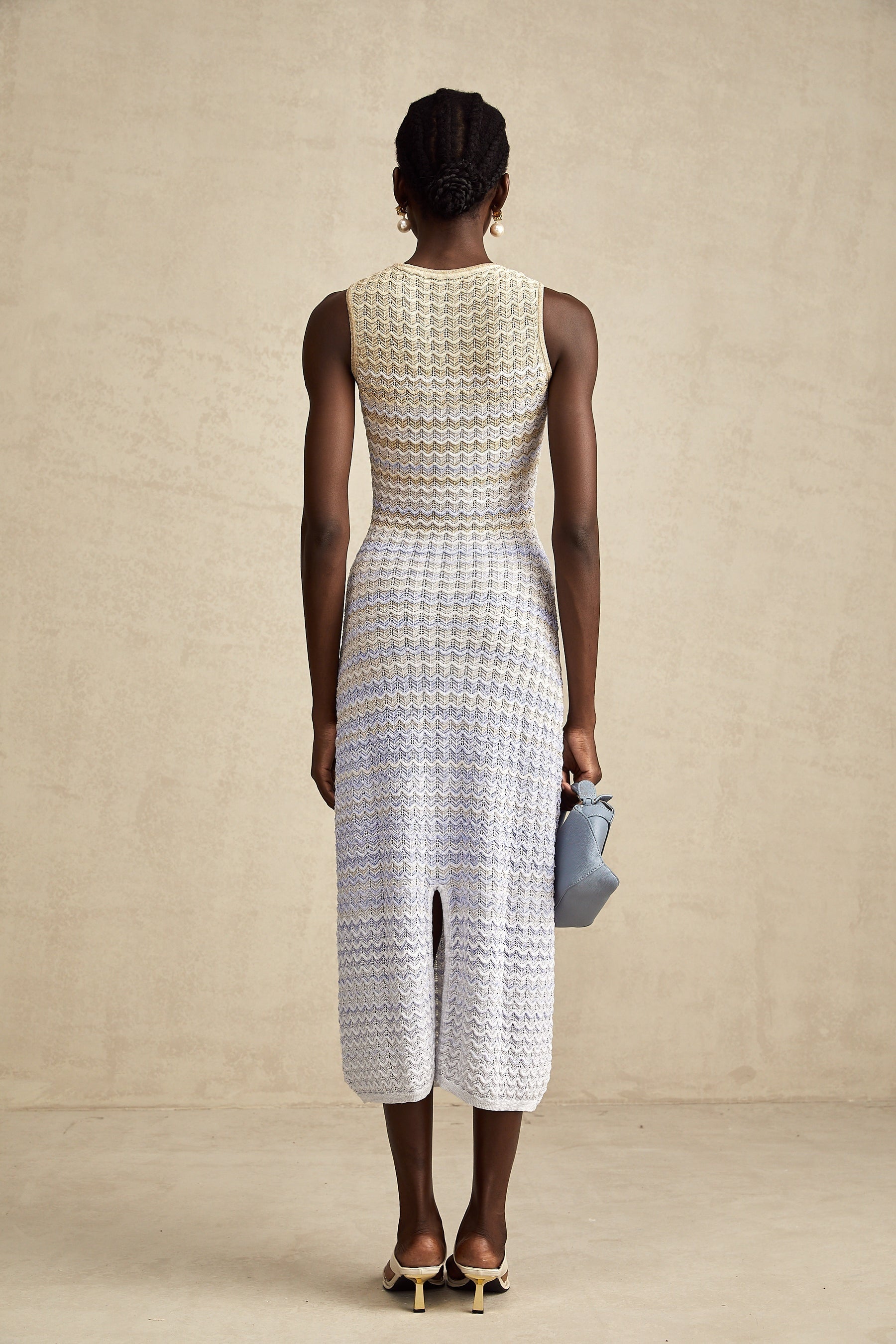 Woman wearing a long ribbed knit dress with contrasting color details and midi length
