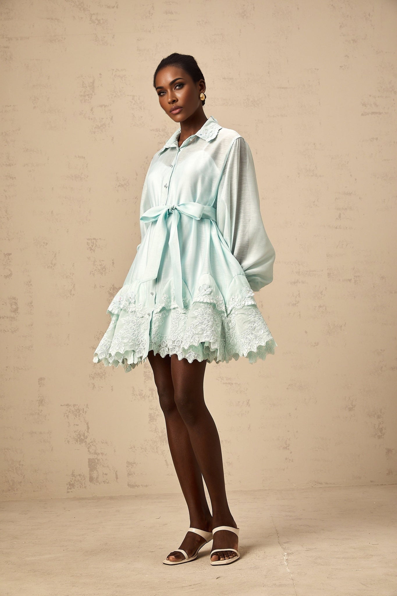 A short green dress with lace panels and a shirtstyle design featuring a collar and buttons