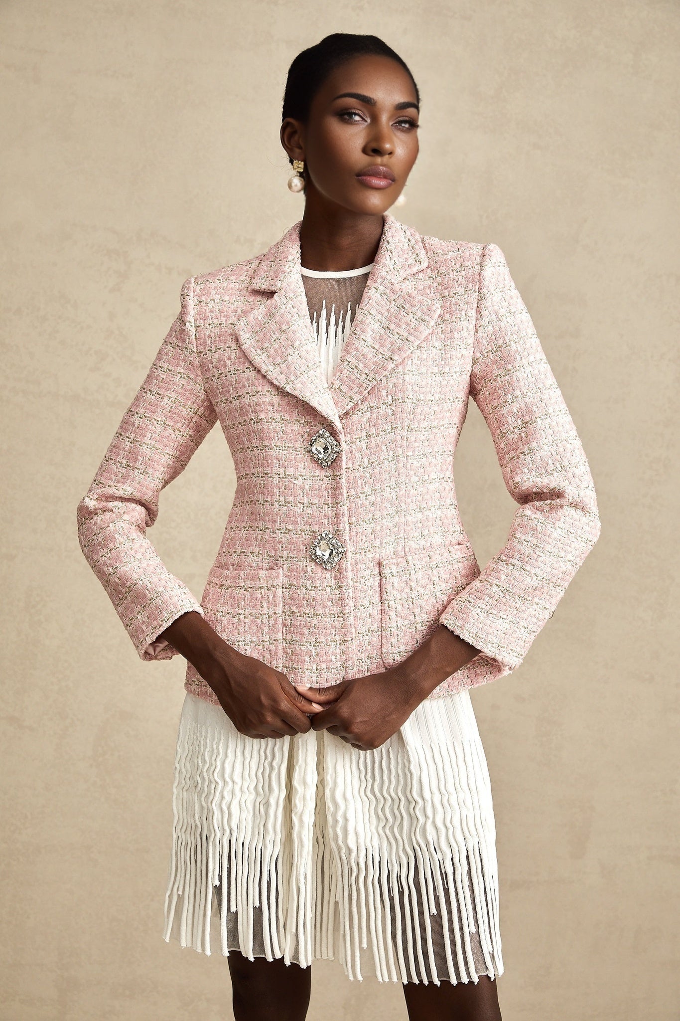 A pink tweed blazer with crystal embellishments featuring a checked pattern