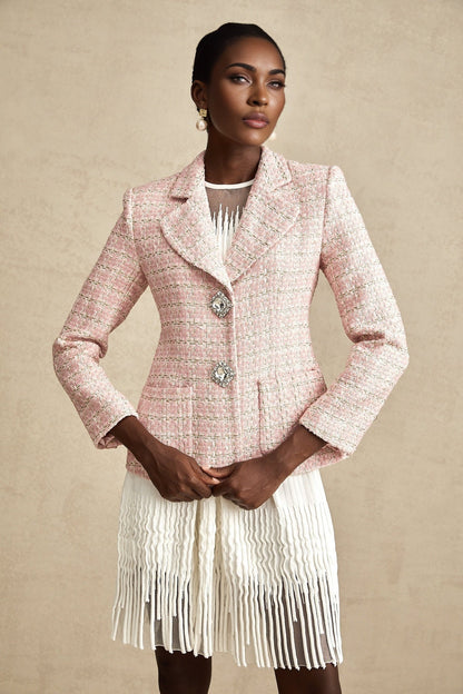 A pink tweed blazer with crystal embellishments featuring a checked pattern