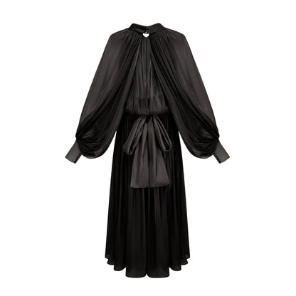 Woman wearing long black pleated satin maxi dress with flowing skirt and fitted bodice