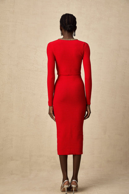 Woman wearing a red knitted cardigan and matching skirt set with embellishments named Axelle
