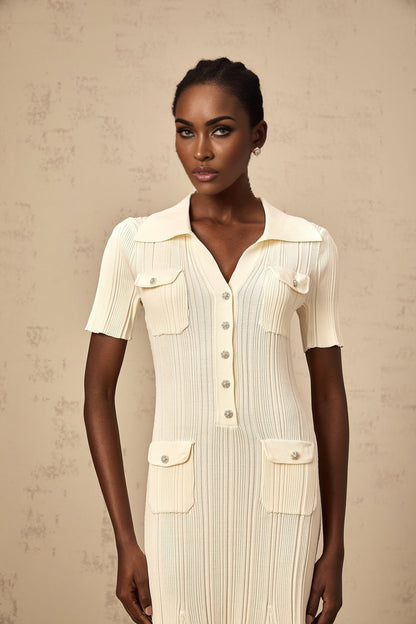 Woman wearing a beige ribbedknit midi dress with long sleeves and a slim fit silhouette standing against a neutral background