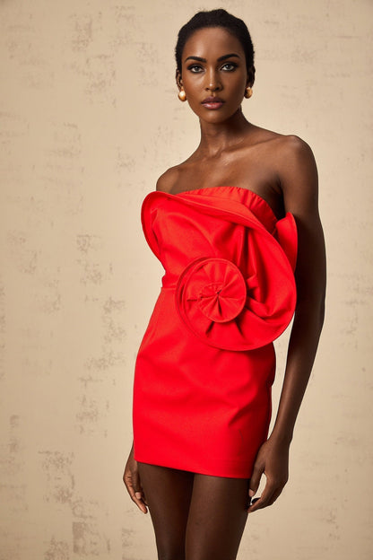 A red mini dress with an offshoulder neckline featuring a large sculptural rose detail on the bodice
