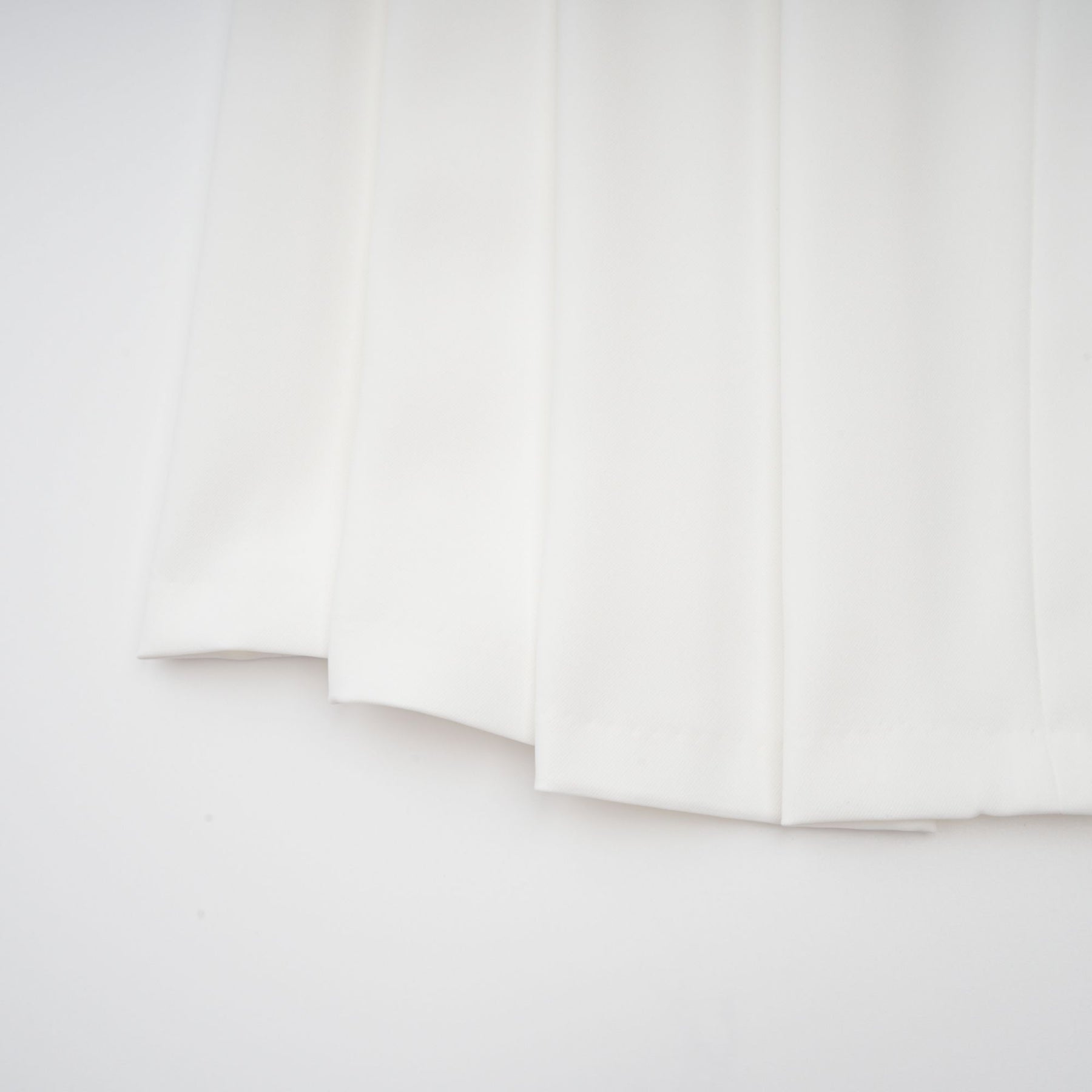 A white matching set featuring a creased top and trousers worn by a model standing against a plain background