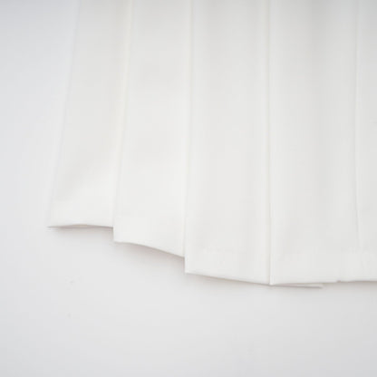 A white matching set featuring a creased top and trousers worn by a model against a plain background